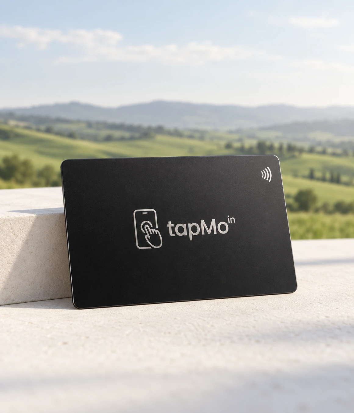 Illustrative black TapMo metal NFC card on stone with a landscape behind
